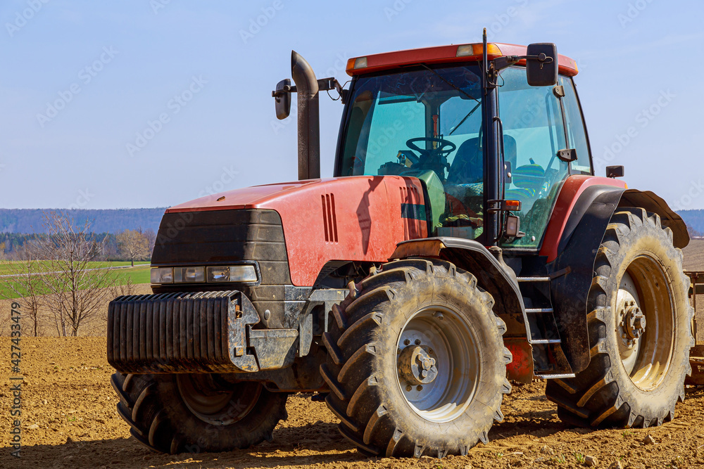 Red tractor on an agricultural field on a sunny spring day. Red tractor on an agricultural field on a sunny spring day.