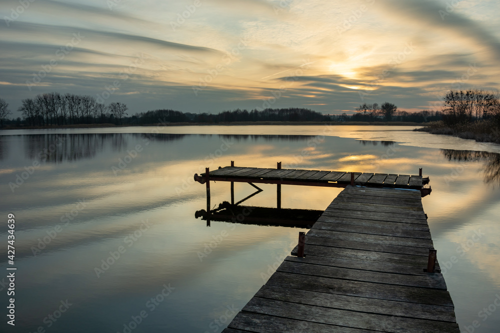 Obraz premium A wooden footbridge on the lake and beautiful evening clouds, Stankow, Lubelskie, Poland