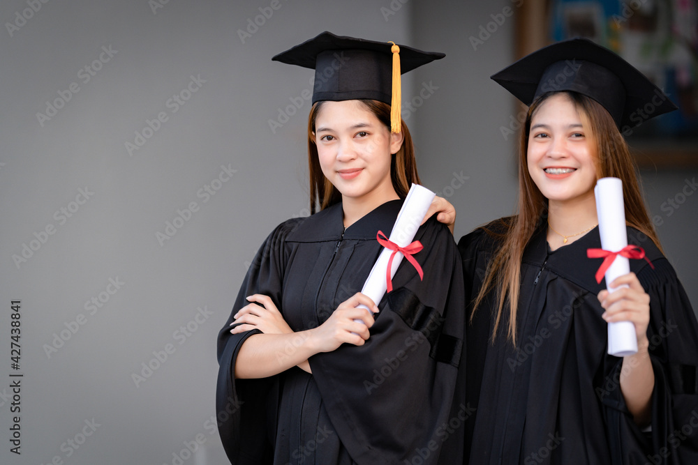 Young happy Asian woman university graduates in graduation gown and mortarboard hold a degree certificate celebrate education achievement in the university campus. Education stock photo Young happy Asian woman university graduates in graduation gown and mortarboard hold a degree certificate celebrate education achievement in the university campus. Education stock photo