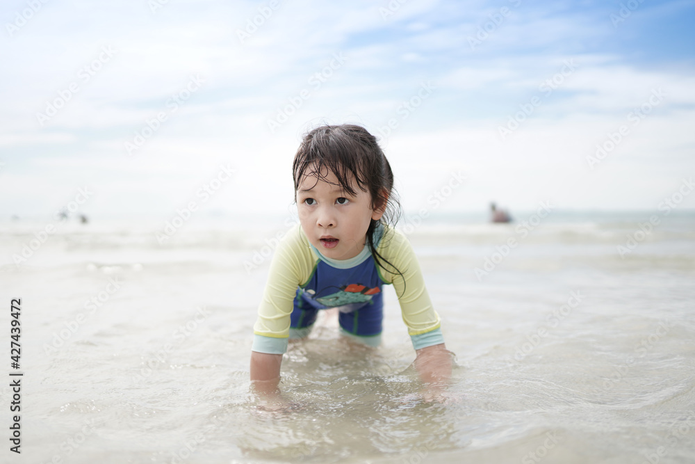 Happy smiling asian little child girl play in the sea by the beach fun leisure concept on summer vacation Happy smiling asian little child girl play in the sea by the beach fun leisure concept on summer vacation