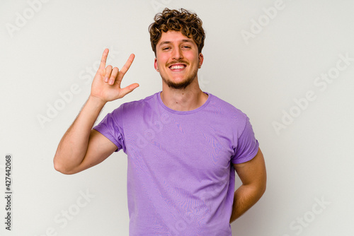 Young caucasian man isolated on white background showing rock gesture with fingers