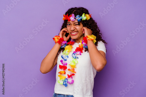 Young Hawaiian woman isolated on purple background covering ears with hands.