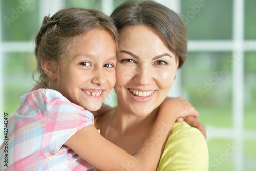 Close-up portrait of a charming little girl hugging with mom at home