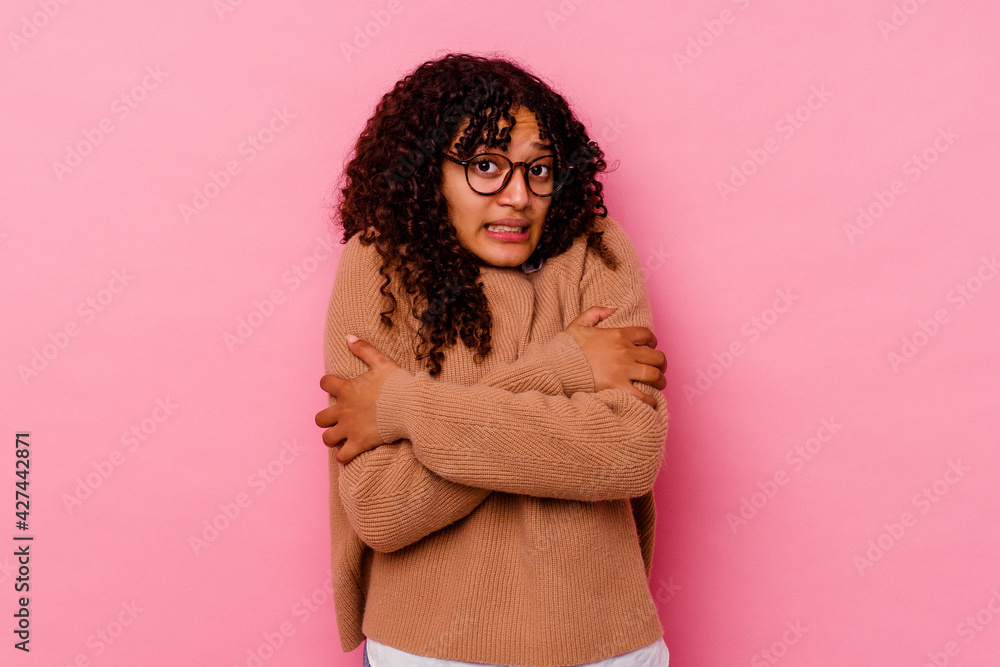 Young mixed race woman isolated on pink background going cold due to low temperature or a sickness. Young mixed race woman isolated on pink background going cold due to low temperature or a sickness.