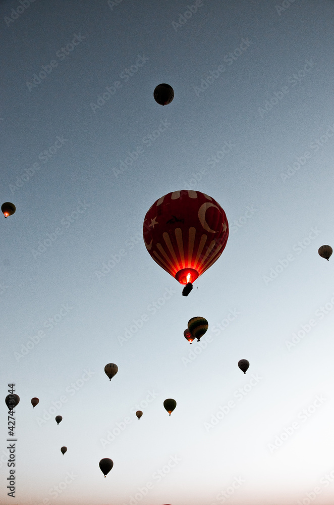 Fototapeta premium TURKEY, CAPPADOCIA, GOREME: Aerial scenic view of hot air balloons flying over mountains landscape with fairy chimneys