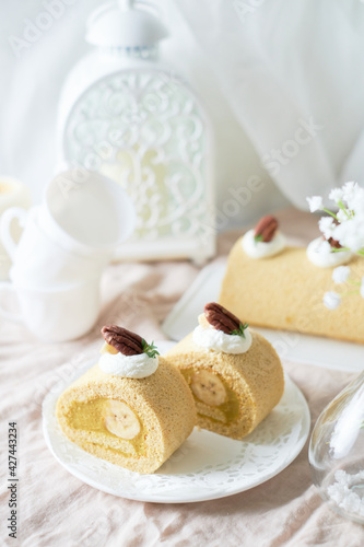 Banana Swiss Roll Cake with banana cream filling set on white cafe table.