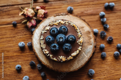Delicious tartlet with fresh blueberries and chocolate, on wooden background. Trendy dessert. Top view