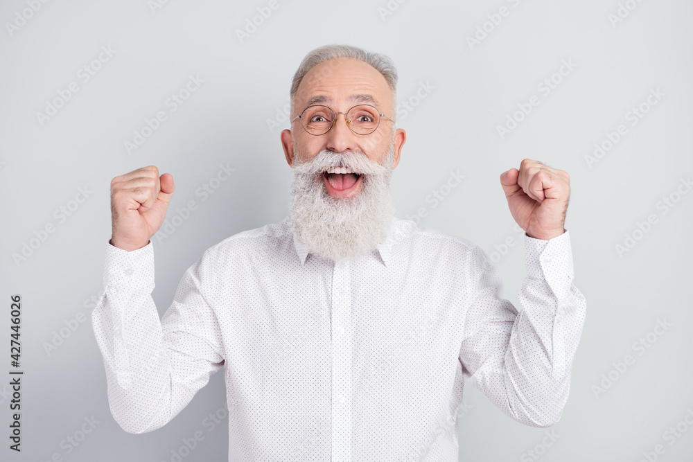 Photo of amazed cheerful old man raise fists winner celebrate good mood isolated on grey color background Photo of amazed cheerful old man raise fists winner celebrate good mood isolated on grey color background