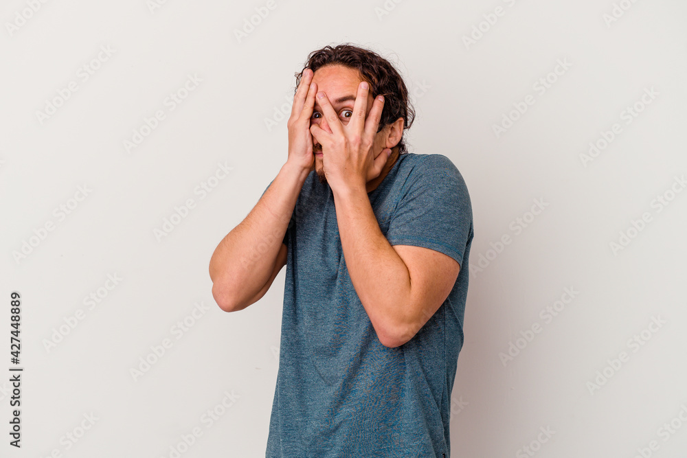 Young caucasian man isolated on white background blink through fingers frightened and nervous. Young caucasian man isolated on white background blink through fingers frightened and nervous.