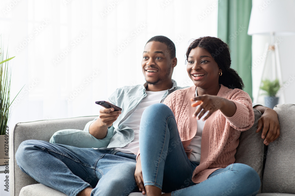 Happy african american family watching TV together at home - obrazy, fototapety, plakaty 