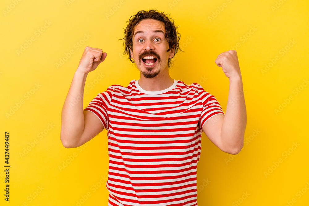Young caucasian man isolated on yellow background cheering carefree and excited. Victory concept. Young caucasian man isolated on yellow background cheering carefree and excited. Victory concept.