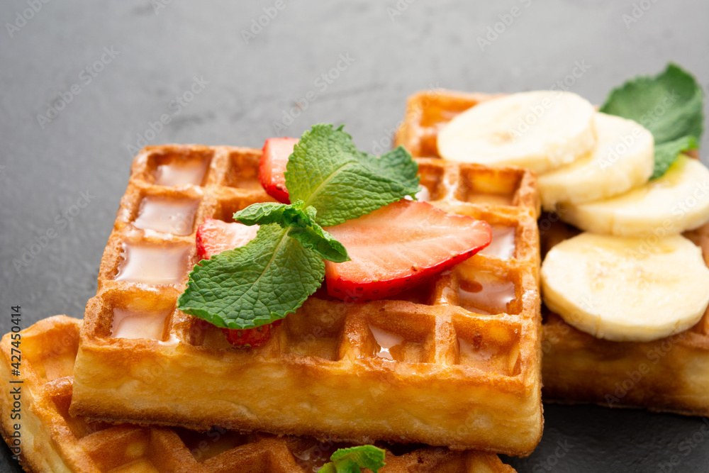 Closeup view of belgium waffles with strawberry and banana with mint Closeup view of belgium waffles with strawberry and banana with mint