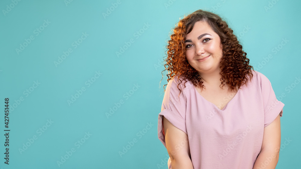 Happy woman. Plus size beauty. Body positive. Model shooting. Conceptual portrait. Smiling fatty lady with curly hairs casual style looking at camera isolated blue copy space. Happy woman. Plus size beauty. Body positive. Model shooting. Conceptual portrait. Smiling fatty lady with curly hairs casual style looking at camera isolated blue copy space.