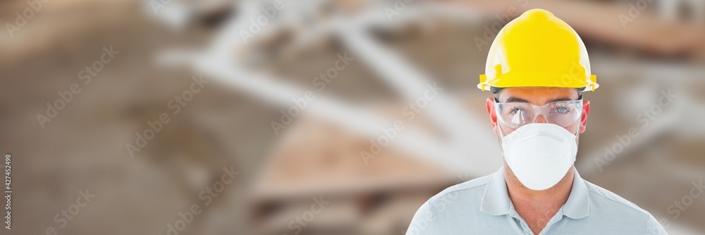 Caucasian male construction worker wearing mask, glasses and helmet, construction site background Caucasian male construction worker wearing mask, glasses and helmet, construction site background