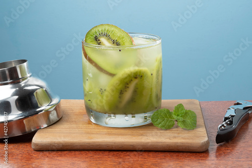 alcoholic drink caipirinha based on kiwi and aguardente distilled cocktail drink and fruits on blue background photo