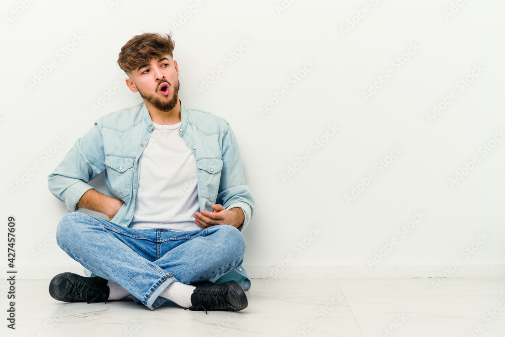Young Moroccan man sitting on the floor isolated on white background suffering a back pain. Young Moroccan man sitting on the floor isolated on white background suffering a back pain.