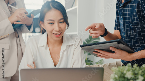 Young coworker asia creative businessman and businesswoman head manager talk coaching plan teach and educate explain project report on laptop paperwork on desk and communicate together at workplace.