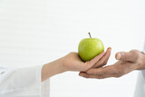 Adult hand receiving green apple. Hands of child girl giving green apple to adult hand with white background