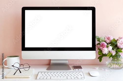 Technology, communication and remote job concept. Front view of nice workplace of female copywriter with fresh flowers, mug and generic desktop computer with blank display for your advertising content