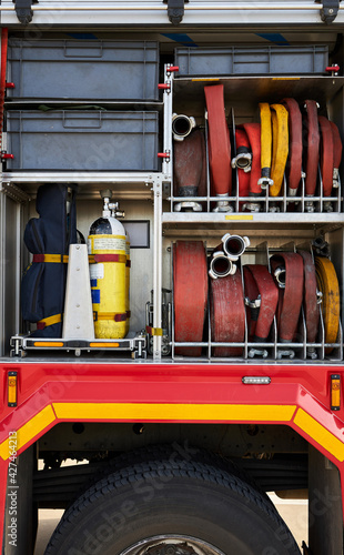 Firefighter tools and fire hoses inside the truck. Side view. Horizontal image