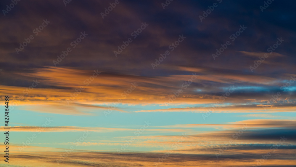 Dark colored clouds in blue sky at sunset 