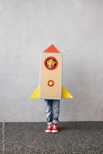 Happy child playing with toy paper rocket