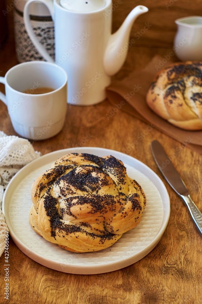 Brioche with cane sugar and poppy seeds on a wooden background. Bun. Top view. Brioche with cane sugar and poppy seeds on a wooden background. Bun. Top view.