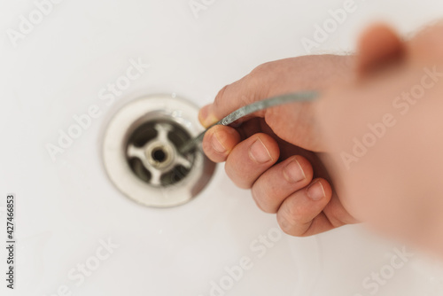 Canvas Print Plumber using drain snake to unclog bathtub.