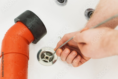 Plumber using drain snake to unclog bathtub. photo