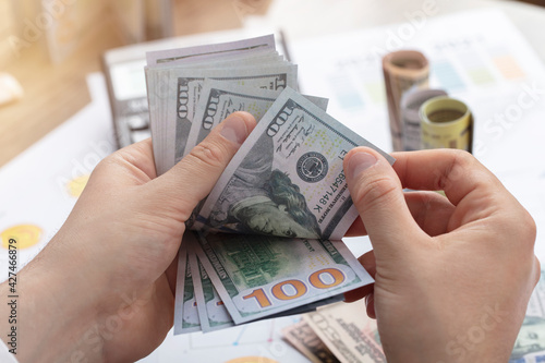 Business financial concept. businessman is looking at financial data on his office desk. Business accounting concept. Counting Money Stack.