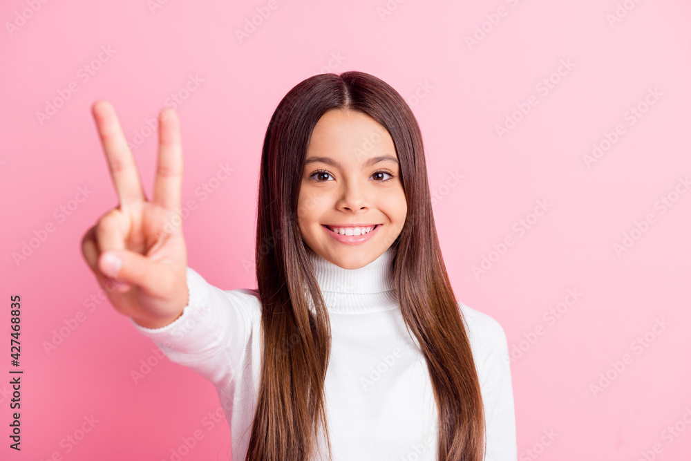 Photo of optimistic nice brunette girl show v-sign wear white sweater isolated on pastel pink color background Photo of optimistic nice brunette girl show v-sign wear white sweater isolated on pastel pink color background