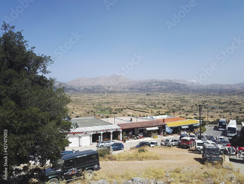 Crete or Kreta, Greece: A wide angle view from top of souvenir shop and cars parked in the middle of deserted area against mountains in a famous greek island