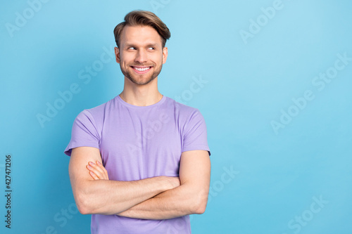 Portrait of positive man folded hands beaming smile look empty space isolated on blue color background