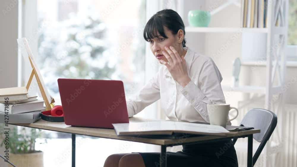 Portrait of desperate shocked young woman looking at laptop screen with dazed facial expression touching face. Stressed young Caucasian CEO having bad news online. Failure and business Portrait of desperate shocked young woman looking at laptop screen with dazed facial expression touching face. Stressed young Caucasian CEO having bad news online. Failure and business