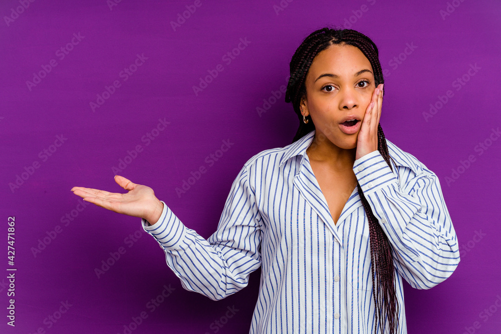 Young african american woman isolated on yellow background Young african american woman isolated on yellow background impressed holding copy space on palm. Young african american woman isolated on yellow background Young african american woman isolated on yellow background impressed holding copy space on palm.