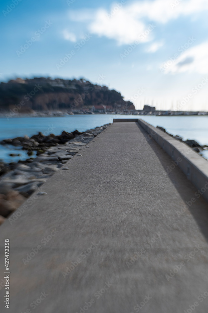 traight walk path at the edge of stone rock beach shore landscape with blurry background