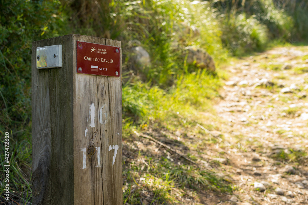 Sign on a wooden post that indicates the Camí de Cavalls path on the island of Menorca. Sign on a wooden post that indicates the Camí de Cavalls path on the island of Menorca.
