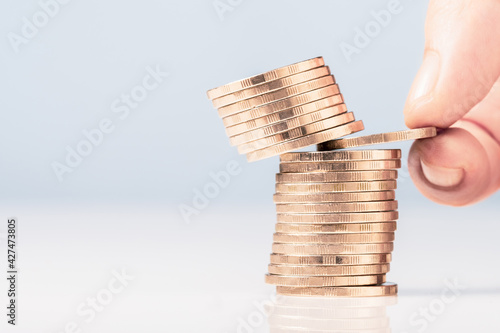 Closeup hand try to pull out a coin in the heap and risk to make the coins above crash down, business dicision, risk investment