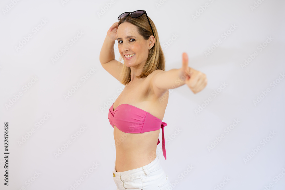 Young smiling woman in bikini showing thumb up isolated over white background. Young smiling woman in bikini showing thumb up isolated over white background.