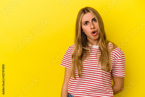 Young blonde caucasian woman isolated on yellow background being shocked because of something she has seen.