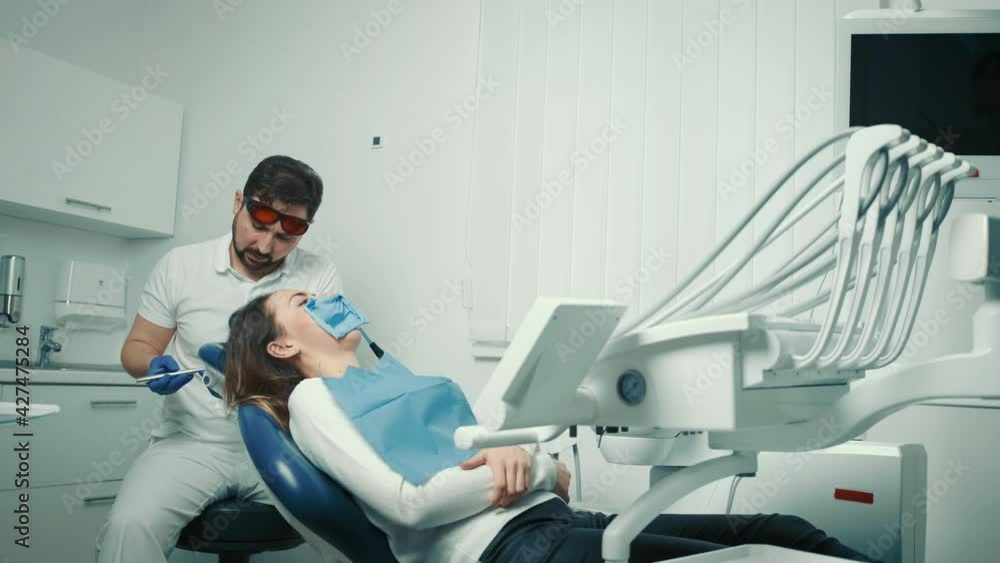 Dentist injects an analgesic injection into the patient before filling ...