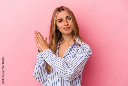 Young blonde caucasian woman isolated on pink background feeling energetic and comfortable, rubbing hands confident.
