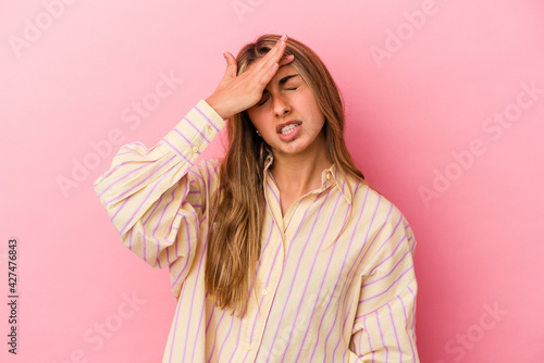 Young blonde caucasian woman isolated on pink background touching temples and having headache.