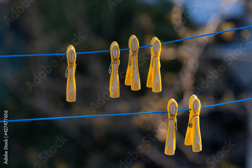 yellow color pegs hanging on clothesline, blue rope, 