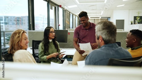 Diverse group of co-workers chatting about upcoming collaboration project holding documents 