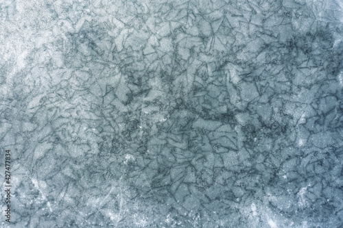 Texture of frozen lake with a lot of cracks on the ice surface.