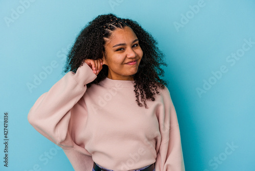 Young african american woman isolated on blue background covering ears with fingers, stressed and desperate by a loudly ambient.