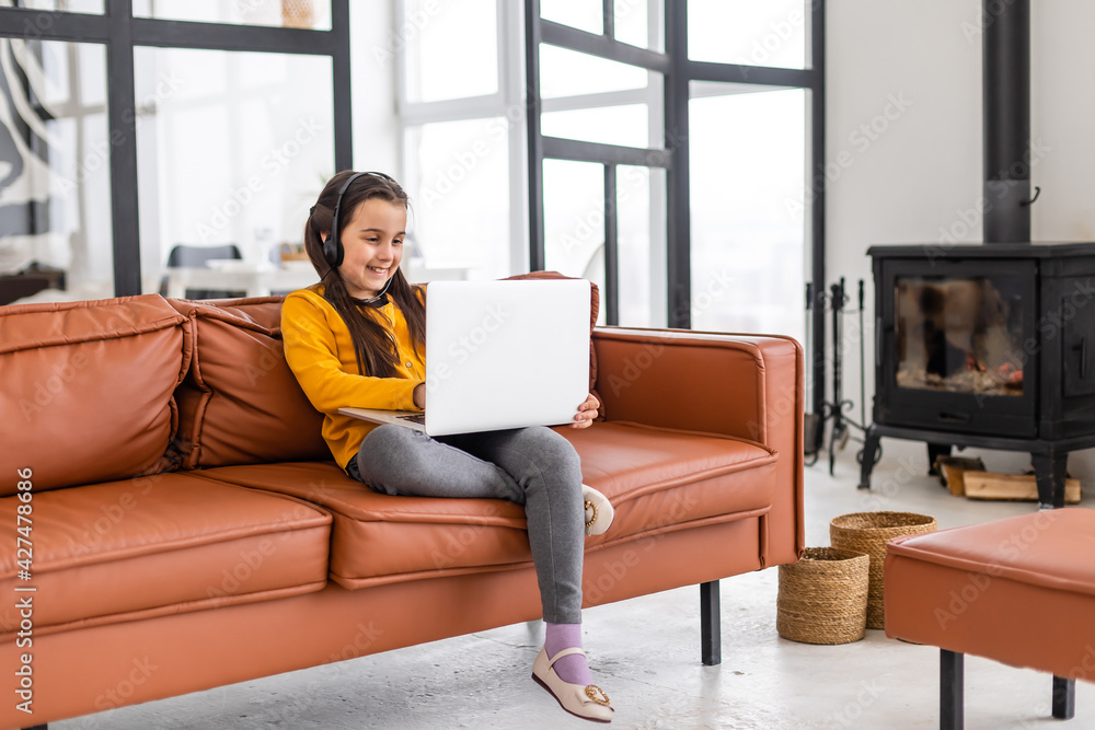Child online. A little girl uses a laptop video chat to communicate learning while sitting at a laptop at home