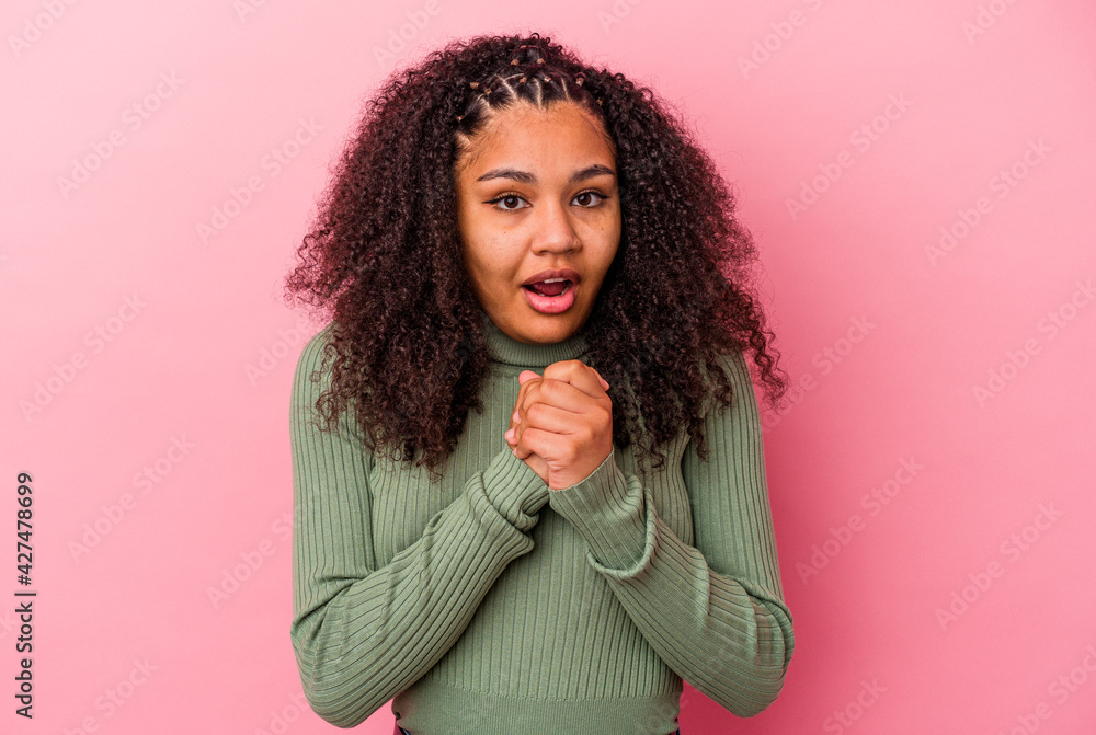 Young african american woman isolated on pink background praying for luck, amazed and opening mouth looking to front. Young african american woman isolated on pink background praying for luck, amazed and opening mouth looking to front.