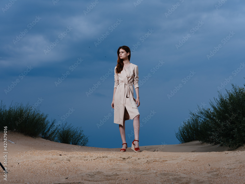 full-length portrait of a woman in a sundress and red sandals on the sand on the beach full-length portrait of a woman in a sundress and red sandals on the sand on the beach
